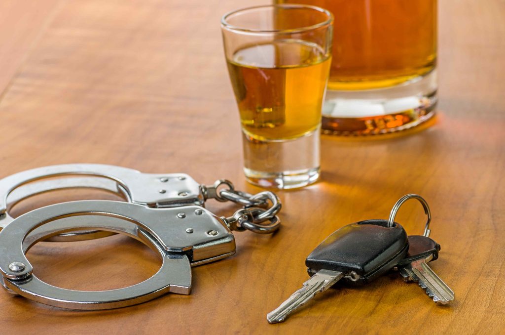 Keys and cuffs with liquor glass at bar equals arrest